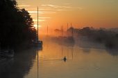 Boats moored on the River Frome during a misty sunrise Wareham Dorset