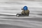 Photographer sat in wind-blown sand Saunders Island Falkland Islands British Overseas Territory November 2016