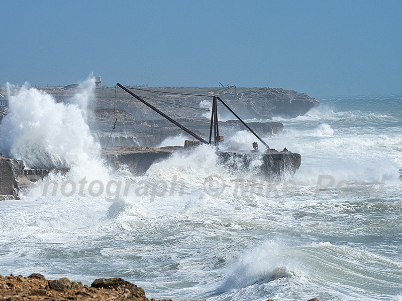 Waves crashing over the boat crane, from Trinity House Obelisk, Portland Bill, Jurrasic Coast, Portland, Dorset, England, UK, August 2020